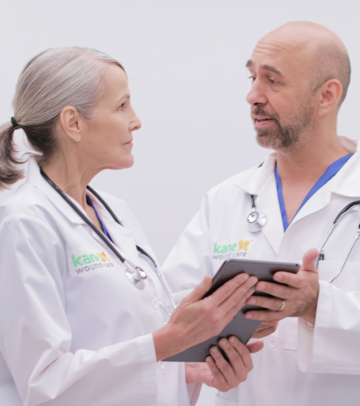 Two doctors talk while holding an ipad tablet